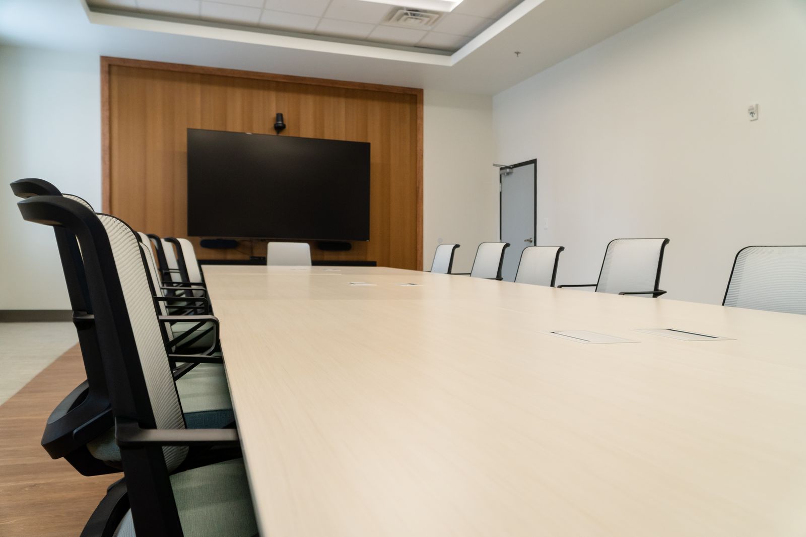 The presentation display and warm wood feature wall beside the conference table